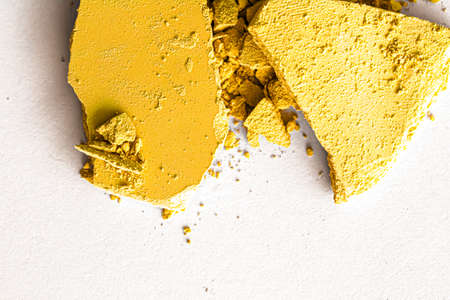 Yellow eye shadow powder as makeup palette closeup isolated on white background, crushed cosmetics...