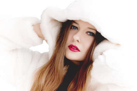 Young woman in fluffy fur coat with hood wrap, warm winter clothing for fashion and Christmas holidays designの写真素材