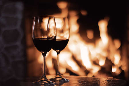 Red wine in front of a fireplace, relaxing atmosphere at homeの写真素材