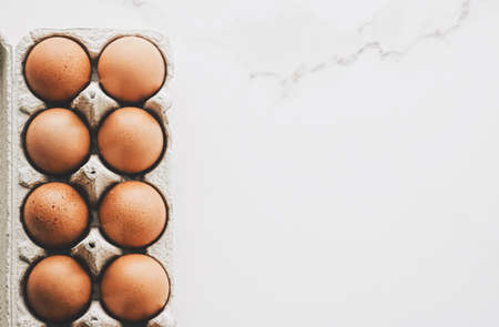 organic eggs in egg box on white marble kitchen table, closeupの写真素材