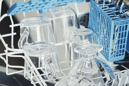 Open dishwasher machine with clean dinnerware in the kitchen, closeupの写真素材