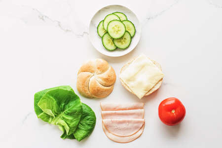 Food products and ingredients for making sandwich. Ham, cheese, burger bun, lettuce, cucumber and...