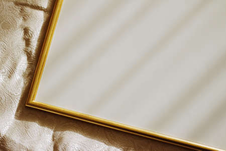 Golden frame for art, poster or photo on bed at sunset, home decor conceptの写真素材