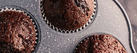 Just baked chocolate muffins in tray, homemade comfort food recipe