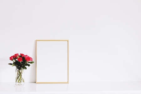 Golden horizontal frame and bouquet of rose flowers on white furniture, luxury home decor and design for mockup creationの写真素材