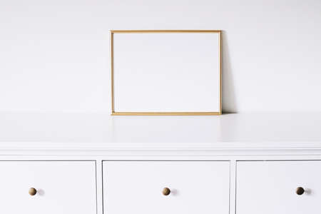 Golden horizontal frame on white furniture, luxury home decor and design for mockup creationの写真素材
