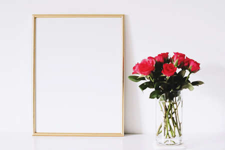 Golden horizontal frame and bouquet of rose flowers on white furniture, luxury home decor and design for mockup creationの写真素材
