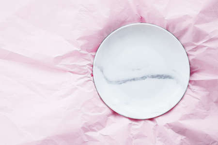 Marble plate inside pink paper packaging as flatlay background, food service flat lay and meal deliveryの写真素材