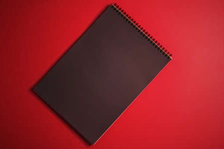 Black notebook on red background as office stationery flatlay, luxury branding flat lay and brand identity design for mockupの写真素材
