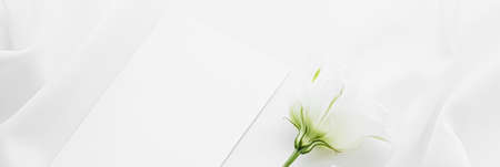 Wedding invitation and white rose flowers on silk fabric as bridal flatlay background, blank paper greeting card and holiday branding, flat lay designの写真素材