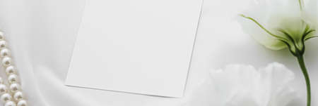 Wedding invitation, white rose flowers and pearls on silk fabric as bridal flatlay background, blank paper greeting card and holiday branding, flat lay designの写真素材