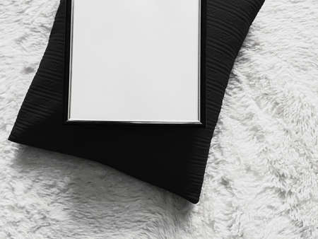 Thin wooden frame with blank copyspace as poster photo print mockup, black cushion pillow and fluffy white blanket, flat lay background and art productの写真素材