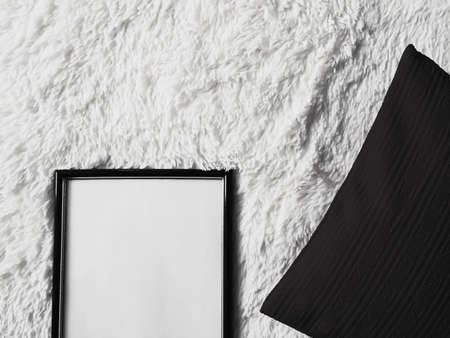 Thin wooden frame with blank copyspace as poster photo print mockup, black cushion pillow and fluffy...