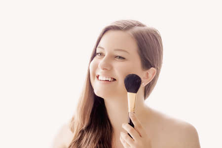 Beautiful woman with makeup brush, perfect skin and shiny hair as make-up, health and wellness...
