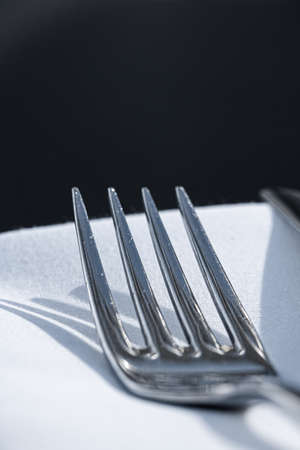 Fork and knife with white napkin on table in luxury restaurant outdoors, fine dining menu for wedding or event and food catering service conceptの写真素材