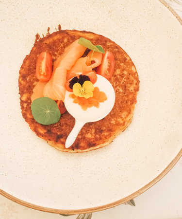 Potato fritter pancake with red caviar, salmon and sour cream in luxury restaurant outdoors in summerの写真素材