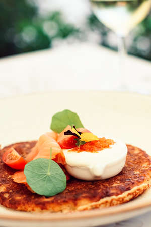 Potato fritter pancake with red caviar, salmon and sour cream in luxury restaurant outdoors in summerの写真素材