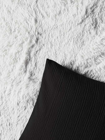 Black cushion throw pillow on white fluffy plaid blanketの写真素材