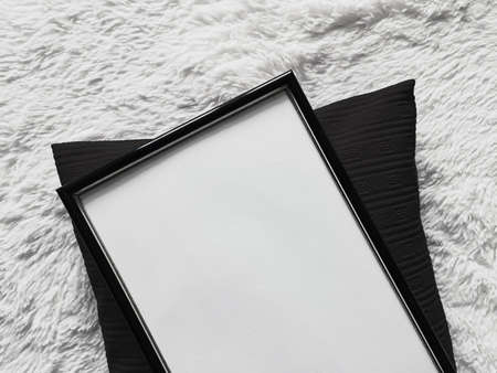 Thin wooden frame with blank copyspace as poster photo print mockup, black cushion pillow and fluffy...