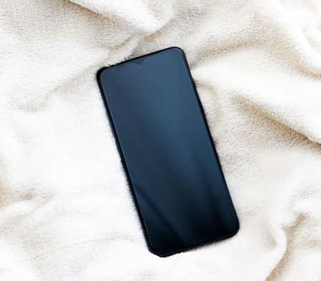 Mobile phone on soft luxury fabric in winter, smartphone flatlay mockup as app template and brand marketing designの写真素材
