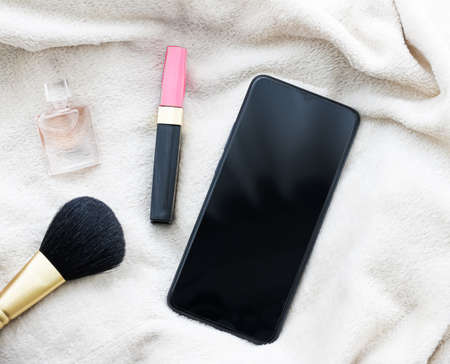Girly flatlay with mobile phone, lipstick, perfume and make-up brush, smartphone mockup as app template and brand marketing designの写真素材