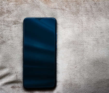 Modern mobile phone with dark blue screen on vintage leather background, smartphone flatlay mockup...
