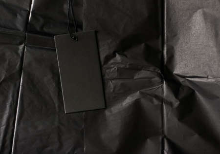 Black tag on tissue paper as luxury shopping flatlay, sustainable fashion and brand label conceptの写真素材