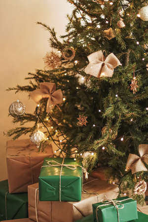 Christmas holiday delivery and sustainable gifts concept. Green gift boxes wrapped in eco-friendly packaging with recycled paper under decorated xmas treeの写真素材