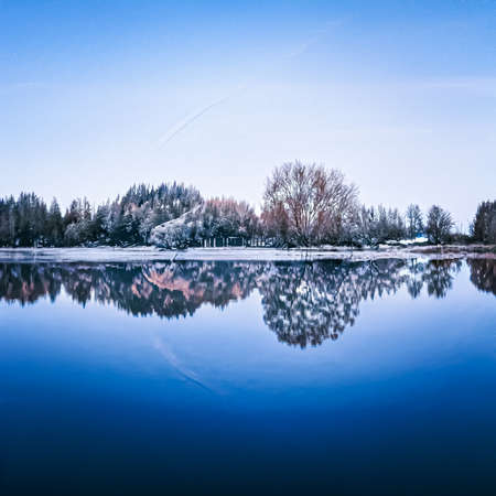 Winter wonderland and Christmas landscape. Frozen lake in snowy mountains and trees covered with snow as holiday backgroundの写真素材