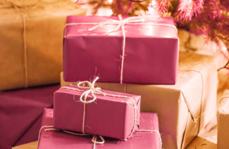 Christmas holiday delivery and sustainable gifts concept. Pink gift boxes wrapped in eco-friendly packaging with recycled paper under decorated xmas treeの写真素材