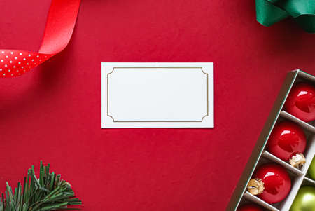Holiday brand identity design and Christmas flatlay concept. White blank business card and xmas ornament and decoration on red paper background as flat lay mockupの写真素材