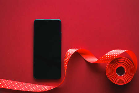 Christmas phone app and holiday message concept. Smartphone with blank black screen and xmas decoration on red background as flat lay mockup designの写真素材