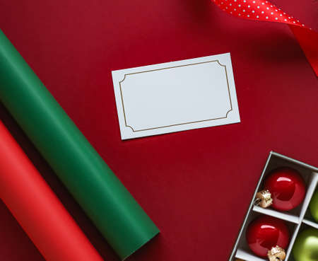 Holiday brand identity design and Christmas flatlay concept. White blank business card and xmas ornament and decoration on red paper background as flat lay mockupの写真素材