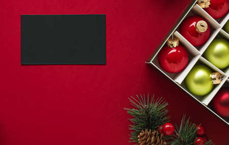 Holiday brand identity design and Christmas flatlay concept. Black blank business card and xmas ornament and decoration on red paper background as flat lay mockupの写真素材