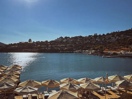 Vintage travel card and hot summer concept. Beach pier with sunbeds and umbrellas at luxury beachfront resort by the sea in summertimeの写真素材