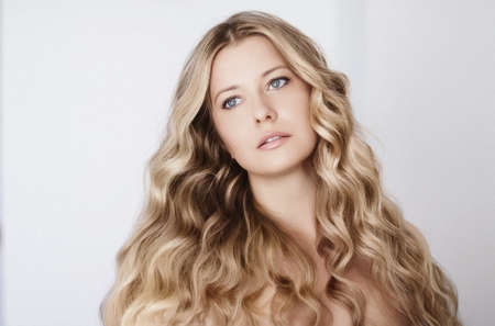 Beauty, hairstyle and natural makeup look. Beautiful woman with long blonde curly hair, flawless skin and organic cosmetic make-up, portrait with soft focus and retro film grain effectの写真素材