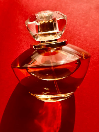 Flacon of perfume made of glass and gold on red backgroundの写真素材