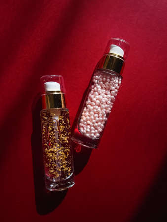 Skincare and make-up cosmetics in glass bottles on red backgroundの写真素材