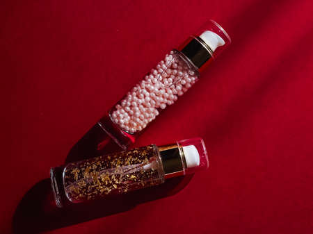 Skincare and make-up cosmetics in glass bottles on red backgroundの写真素材