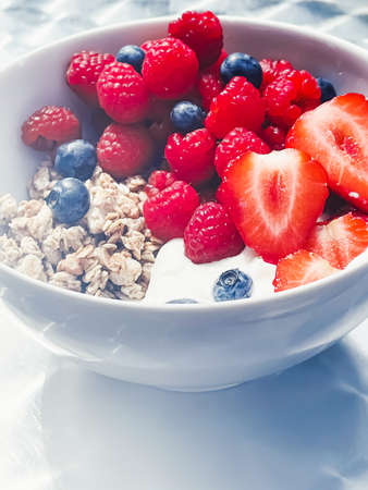 Delicious breakfast with cereal, yogurt, strawberries, raspberries and bluberries in the garden...