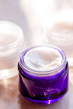 Moisturising beauty cream jars, skincare and spa cosmetics on stone background in summer at sunset,...
