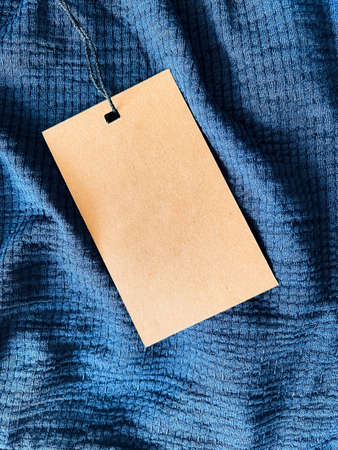 Blank fashion label tag, sale price card on luxury fabric background, shopping and retail concept