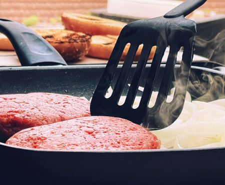 Cooking minced beef burger on cast iron grill skillet outdoors, red meat on frying pan, grilling...