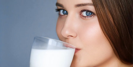 Happy young woman drinking milk or protein milk shake cocktail, healthy drink for diet and wellness conceptの写真素材