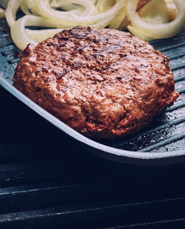 Cooking minced beef burger on cast iron grill skillet outdoors, red meat on frying pan, grilling...