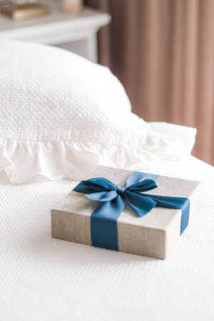Holiday present and luxury online shopping delivery, wrapped linen gift box with blue ribbon on bed in bedroom, chic countryside style, close-upの写真素材