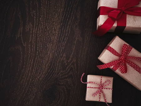 Christmas gifts and traditional holiday presents, classic xmas gift boxes on wooden background, present wrapped in craft paper with red ribbon, vintage rustic countryside style for seasonal holidays designの写真素材