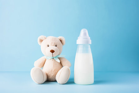 Baby bottle with milk and teddy bear for a baby boy on blue background. Generative AI.の素材