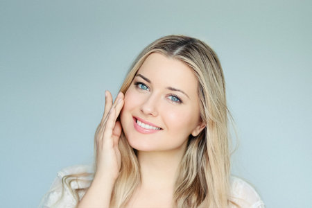 Natural beauty, skincare and cosmetics, smiling blonde woman with blue eyes and radiant face applying moisturiser, light mint backgroundの写真素材