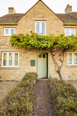 Traditional stone cottage with an open door, inviting visitors into a cozy, character filled residence. Cotswolds countryside, Englandの写真素材